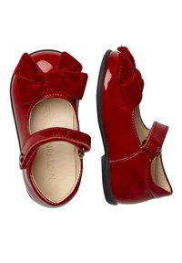 Zapatos Mary Jane de charol rojo con un lazo de terciopelo, que cuentan con una correa ajustable y una suela de goma negra para mayor tracción.