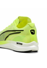 Puma hardloopschoen in een levendig neongeel met zwarte accenten, met een ademende mesh bovenkant, een gevoerde zool en "NITRO" merkbranding.