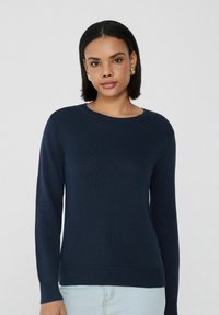 Marineblauer, gerippter Strickpullover mit langen Ärmeln und Rundhalsausschnitt, aus weichem Material gefertigt. Figurschmeichelnder Schnitt mit glatter Textur.