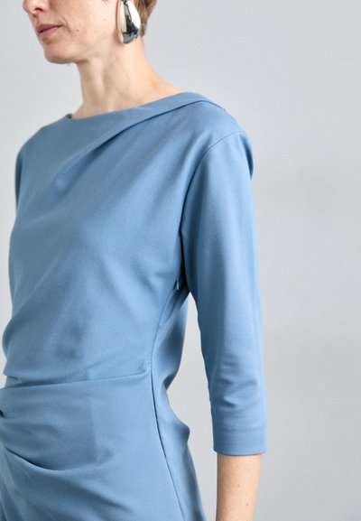 Vestido largo azul de mangas largas con escote drapeado y detalle plisado en la cintura. Tejido suave, diseño ajustado y sin cierres visibles.
