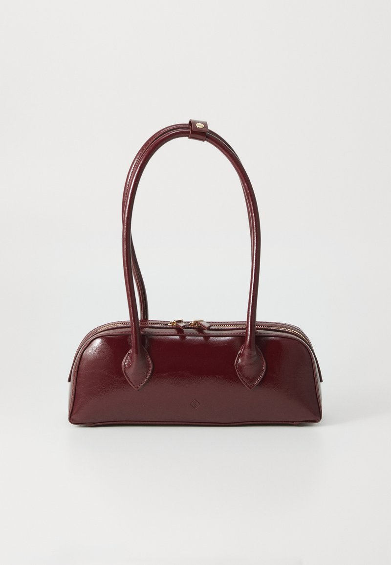Sac à main en cuir bordeaux avec une forme courbée, deux poignées, fermeture éclair et détails de couture subtils. Fini lisse et brillant.