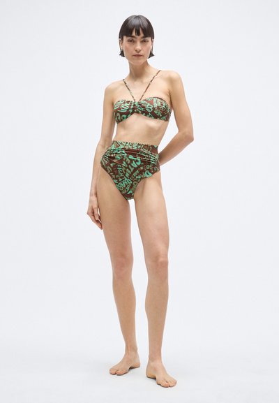 Fürdőruha szett, amely csavart bandeau felsőből és magas derekú alsóból áll. Rugalmas barna anyagból készült, zöld absztrakt szövegmintázattal.