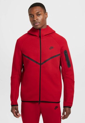 Red Nike hoodie with black accents and zipper pocket. Features a high collar and a fitted design. Made of soft, textured fabric.