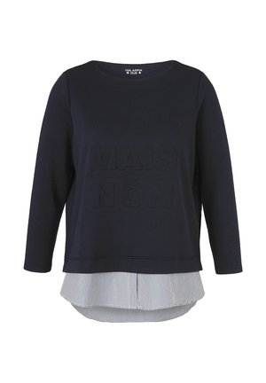 Marineblaues Langarmshirt mit erhabenen Schriftzügen und einem mehrlagigen Saum, der ein weißes und marineblau gestreiftes vertikales Stoffdetail zeigt.