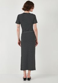 Juodai baltais dryžiuotas maxi suknelė su trumpomis rankovėmis, prigludusia siluetu, šoninėmis plyšėmis ir lygiu paviršiumi. Midsleeve ilgio ir kulkšnies ilgio juostos.
