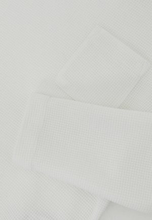 Fehér, rácsmintás, texturált szövet, feltekert ujjú szegéllyel és egy kis felvarrt zsebbel az ujjon.