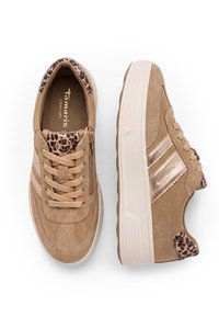 Ζευγάρι μπεζ sneakers από σουέτ με χοντρές λευκές σόλες, λεπτομέρειες με σχέδιο λεοπάρδαλη στη φτέρνα και τη γλώσσα και πλαϊνό φερμουάρ στο αριστερό παπούτσι.