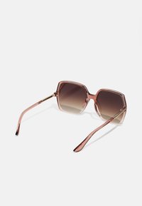 Pink, hexagonal sunglasses with gradient lenses. Transparent frame and slender arms, featuring metallic accents on the hinges.