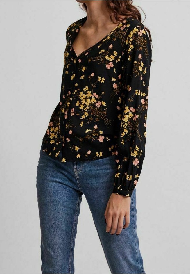Blusa nera a fiori con fiori gialli e rosa, scollatura a V, maniche lunghe e polsini elasticizzati. Indossata con jeans in denim blu.