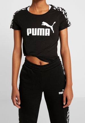 Czarny krótki t-shirt Puma z białym logo i wzorzystymi paskami na ramionach, zestawiony z czarnymi dresami Puma z białym logo i bocznymi detalami.