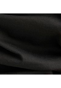 Närbild av svart ribbat tyg med subtila veck och textur i mjukt, stretchigt material.