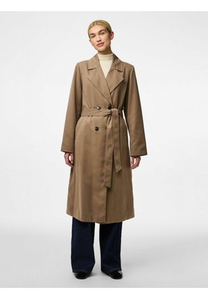 Brun trenchcoat med dobbeltradet design, brede revers, belte og to svarte knapper. Glatt stoff, kne-lengde, kombinert med vide jeans.