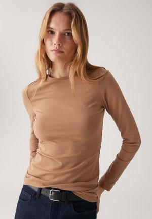 Maglietta marrone a maniche lunghe in un tessuto morbido ed elastico con design aderente. Collo a giro e texture liscia, abbinata a jeans blu scuro e una cintura nera.