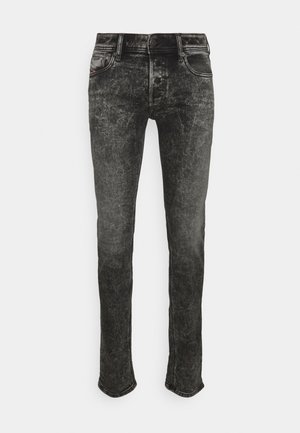 Jean slim noir acid-wash avec poches avant, passants de ceinture et fermeture par bouton, présenté sur fond blanc.