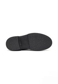 Suela de zapato de goma negra con una superficie texturizada, punta curva y un ligero tacón. Presenta un borde suave cerca del área del arco.