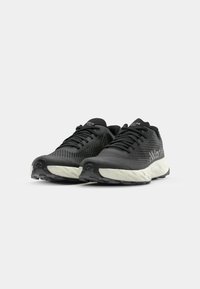 Scarpe da ginnastica nere con tomaia testurizzata, chiusura con lacci e suola imbottita in fondo bianco. Presentano una marcatura discreta sul lato.