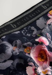 Black floral scarf featuring large pink and yellow flowers with grey accents. Includes a textured black label with "b by Ted Baker."