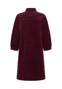Bordeaux kleurige korduroy jurk met lange mouwen en knielengte, voorzien van een kraag en elastische manchetten, van achteren weergegeven op een witte achtergrond.