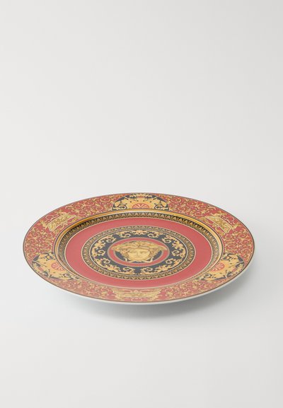 Κεραμικό πιάτο με κόκκινο και χρυσό μπαρόκ μοτίβο. Το κεντρικό μετάλλιο έχει σχεδίαση με πρόσωπο, περιβαλλόμενο από περίτεχνες λουλουδένιες λεπτομέρειες.