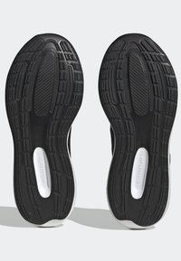 Semelles de chaussures de sport noires en caoutchouc texturé, comportant un détail Cloudfoam et un motif de semelle pour une meilleure adhérence. Accents blancs sur les bords.