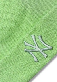 Grüne Strickmütze mit einem erhabenen, geprägten weißen "NY"-Logo. Glatte Textur und runde Form, mit einem subtilen gewebten Muster auf dem Material.