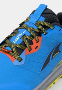 Baskets de course bleues présentant une tige texturée, des accents noirs, des lacets à motif jaune et noir, et un détail de design rouge près des œillets.