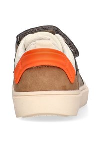 Zapatilla marrón con un talón de ante suave y un acento de goma naranja. Presenta agujetas blancas y una entresuela color crema. Cinta de velcro en la parte superior.