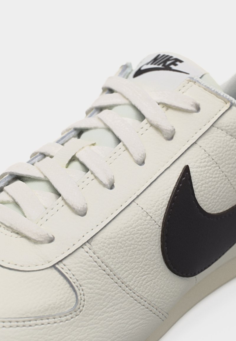 Nahaufnahme eines weißen Nike-Sneakers aus Leder mit weißen Schnürsenkeln und schwarzem Nike-Swoosh an der Seite.