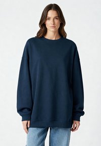 Tumši zils pārpildīts džemperis, izgatavots no mīksta materiāla ar ribotām aprocēm un maliņu, ar klasisku zemu kakla izgriezumu un brīvu piegriezumu.