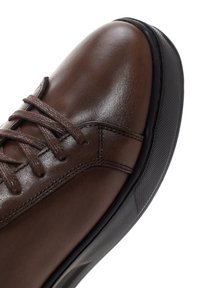 Brown leather shoe with smooth texture, round toe, and traditional lace-up design; features a textured black sole for traction.