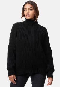 Schwarzer übergroßer Pullover mit hohem Rollkragen, grob gestrickter Textur, überschnittenen Schultern sowie gerippten Bündchen und Saum.