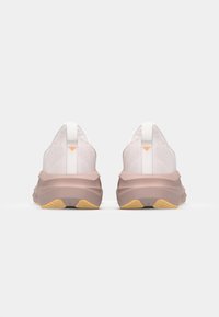 Zapatillas deportivas ligeras con parte superior de malla blanca, entresuela de un suave color rosa y suela de goma texturizada con acentos amarillos.