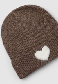 Cappello a beanie lavorato a maglia marrone con texture a coste e una toppa a forma di cuore in peluche bianco bordata di marrone sul polsino.