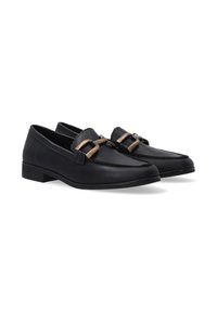 Een paar zwarte leren dress loafers met lage hakken en decoratieve gouden gespen op elke schoen, weergegeven op een witte achtergrond.