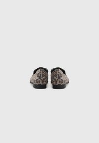 Leopard print slip-on shoes feature a low heel, rounded toe, and black accents, with a textured fabric upper and smooth sole.