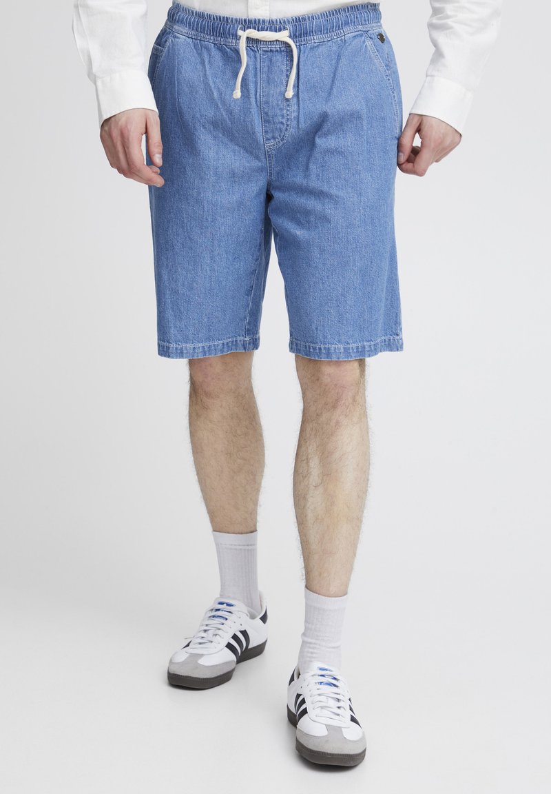 Shorts de mezclilla azul claro con cintura elástica y cordón. Corte recto, que llega justo por encima de la rodilla, con bolsillos laterales.