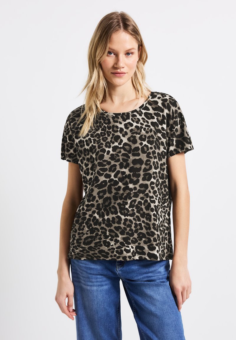 T-shirt a maniche corte con stampa leopardata in tonalità beige e nera, con collo rotondo e vestibilità rilassata, abbinato a jeans blu.