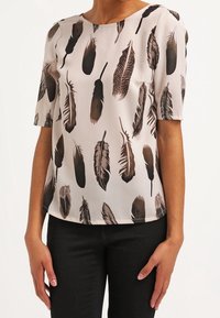 Blusa a maniche corte in tessuto rosa chiaro con motivo di piume marrone scuro, caratterizzata da un collo rotondo e un taglio dritto.