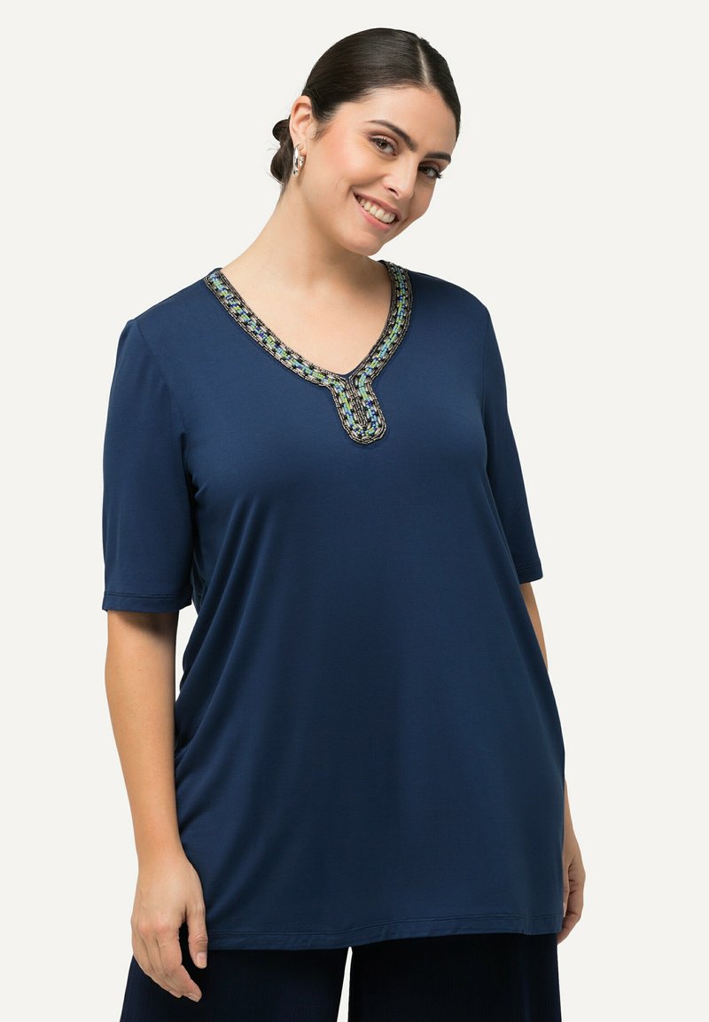 Námořnická modrá tunika s krátkým rukávem ve tvaru V, se zdobeným, vícebarevným vyšívaným v ýstřihem a volným, pohodlným střihem.