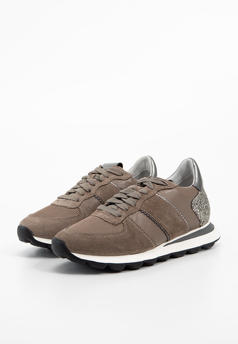 Un par de zapatillas de ante y malla marrones con cordones, con mediasoles blancos, suelas negras y acentos de purpurina plateada en el talón.