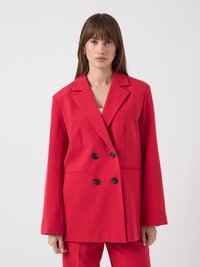 Veste rouge à double boutonnage avec une coupe cintrée, boutons noirs, revers crantés et poches latérales. Tissu lisse et design légèrement oversize.