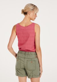Roze mouwloze top met gestructureerde strepen, gecombineerd met olijfgroene short met twee achterzakken en opgerolde manchetten, elastische tailleband.