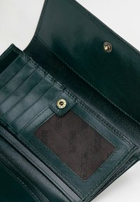 Dunkelgrünes Lederportemonnaie mit Kartenfächern, einem transparenten ID-Halter und einem Druckverschluss. Glatte Textur mit minimalem Zubehör.