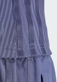 Gestructureerde, diepblauwe stof met verticale plooien en een gestikt zoom. Bevat de tekst "AEROREADY" in lichte contrastkleur aan de zijkant.