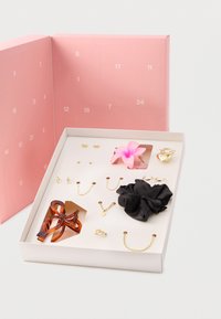Σετ αξεσουάρ σε ροζ κουτί, που περιλαμβάνει μαύρο λαστιχάκι μαλλιών, χρυσά κοσμήματα, κλιπ φιογκάκι από ρητίνη και ροζ λουλούδι.