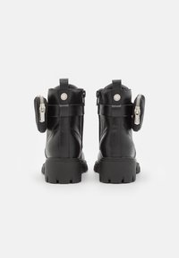 Zwarte leren enkellaarsjes met een dikke zool. Opvallende details zijn de ritsen en kleine ritsvakjes aan de zijkanten.