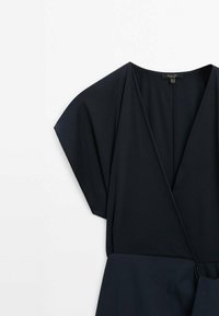 Robe bleu marine au design portefeuille et à manches dolman courtes. Fabriquée en tissu lisse avec une ceinture nouée pour une silhouette structurée.