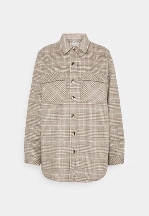 Veste-chemise à carreaux beige et blanc avec deux poches à rabat à l'avant et un col.