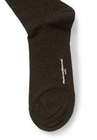 Mørkebrune sokker lavet af glat stof, med en ribbet design og en hvid logo tekst ved anklen. Rund tå og ensfarvet.