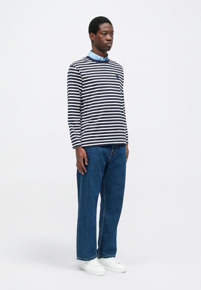 Striped long-sleeve shirt in navy and white, collared blue undershirt, paired with loose blue jeans and white sneakers.